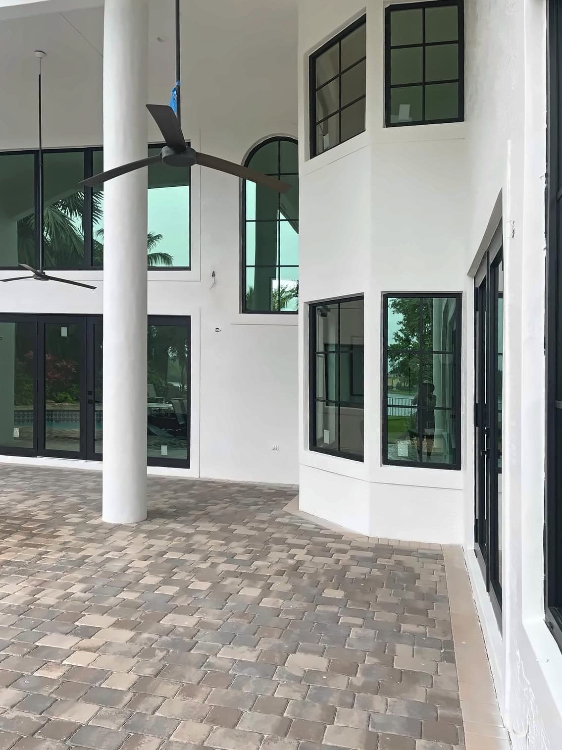 Black-framed windows and doors along a covered lanai with paver flooring